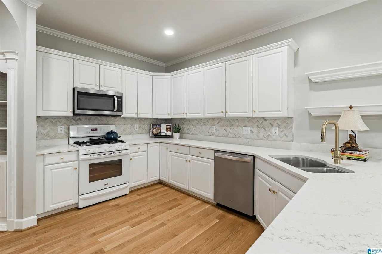 Renovated kitchen with quartz counters, white cabinetry and stainless appliances